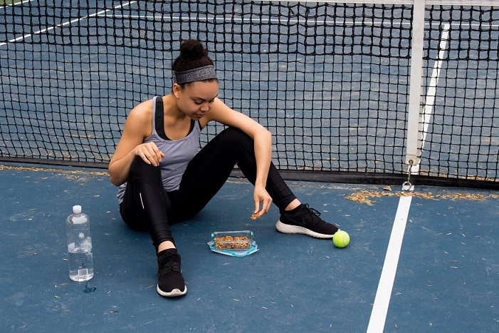 woman eating snacks at tennis court