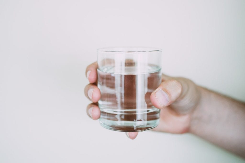 hand holding a glass of water to help with portion control