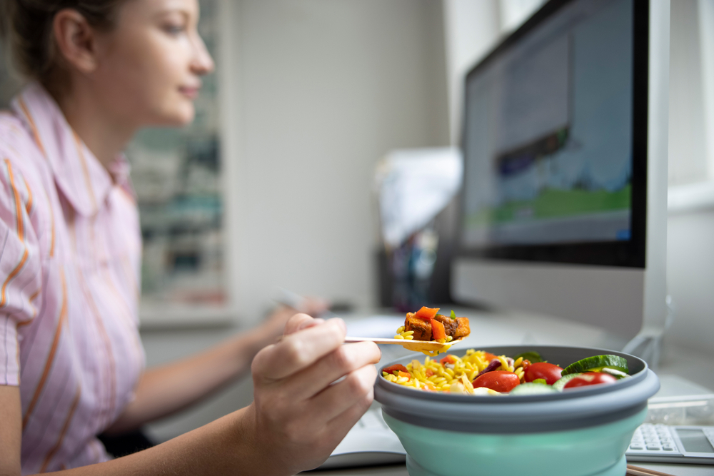 Woman sitting in front of a computer screen with her lunch bowl