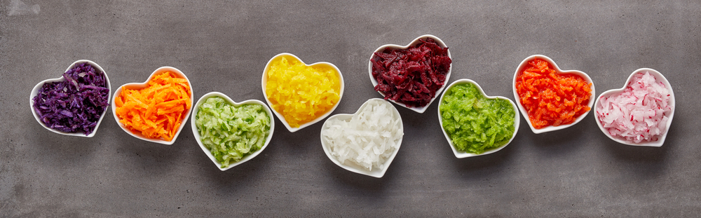Different shredded vegetables in small, white, heart-shaped bowls.