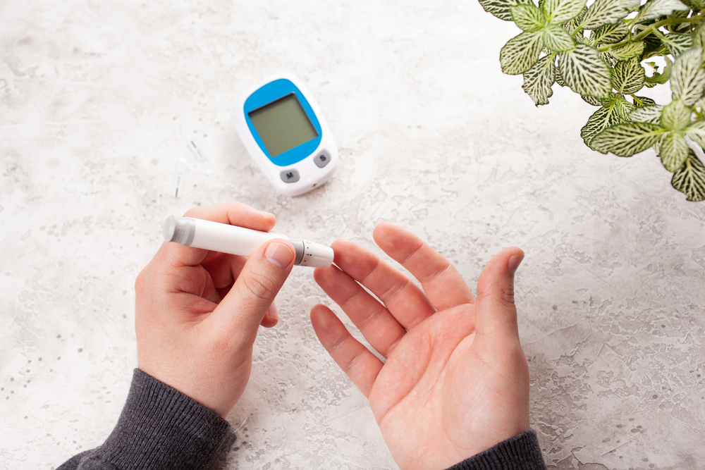 Ketosis/Keto blood tests are like diabetes tests, which is pictured here. A person pricks their middle finger with a lancet to prepare a home blood sugar test.